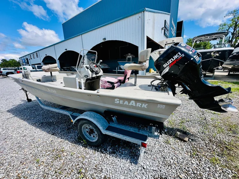 Slide: The Image of 2008 SeaArk x160 boat with Suzuki motor on trailer, parked outside a blue building. - 4