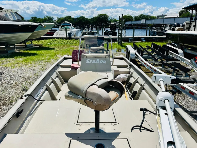 Slide: The Image of 2008 SeaArk x160 boat docked, featuring seating and steering console, with trailers and water in background. - 8