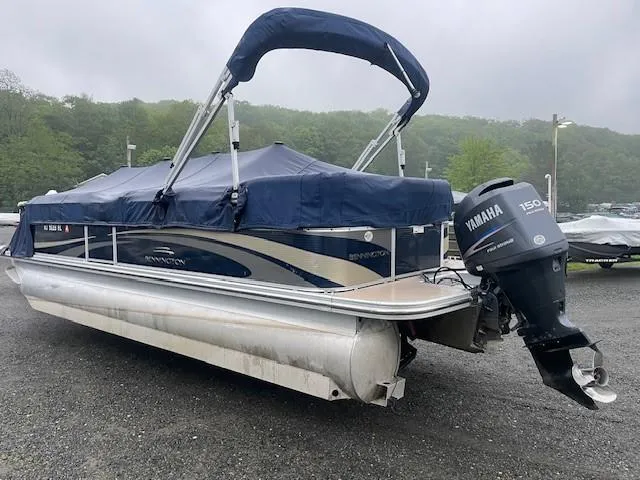 Slide: The Image of 2011 Bennington 2275GLi pontoon boat with Yamaha 150 outboard motor, covered and parked outdoors. - 2