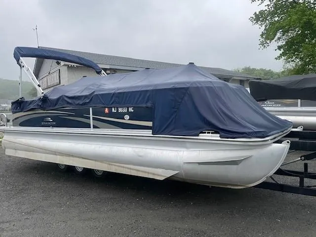Slide: The Image of 2011 Bennington 2275GLi pontoon boat covered, parked on a trailer near a building. - 4