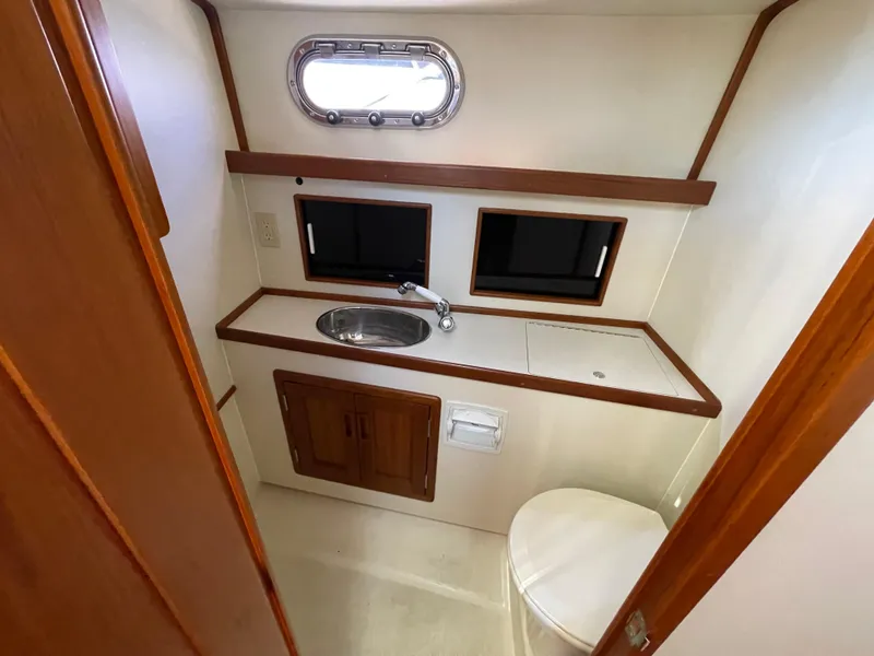 Slide: The Image of Fortier 30 yacht bathroom interior with sink, toilet, and porthole, 2015 model. - 22