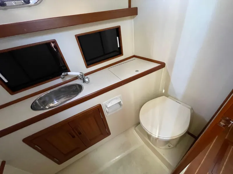 Slide: The Image of 2015 Fortier 30 boat bathroom with sink, toilet, and wooden cabinetry. - 24