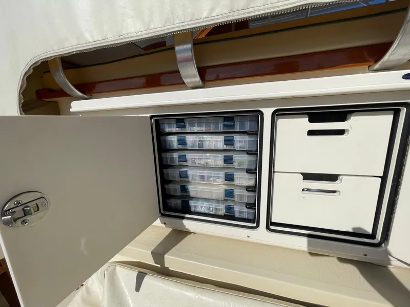 Slide: The Image of Open storage compartment on 2015 Fortier 30 boat with organized tackle boxes and drawers. - 41