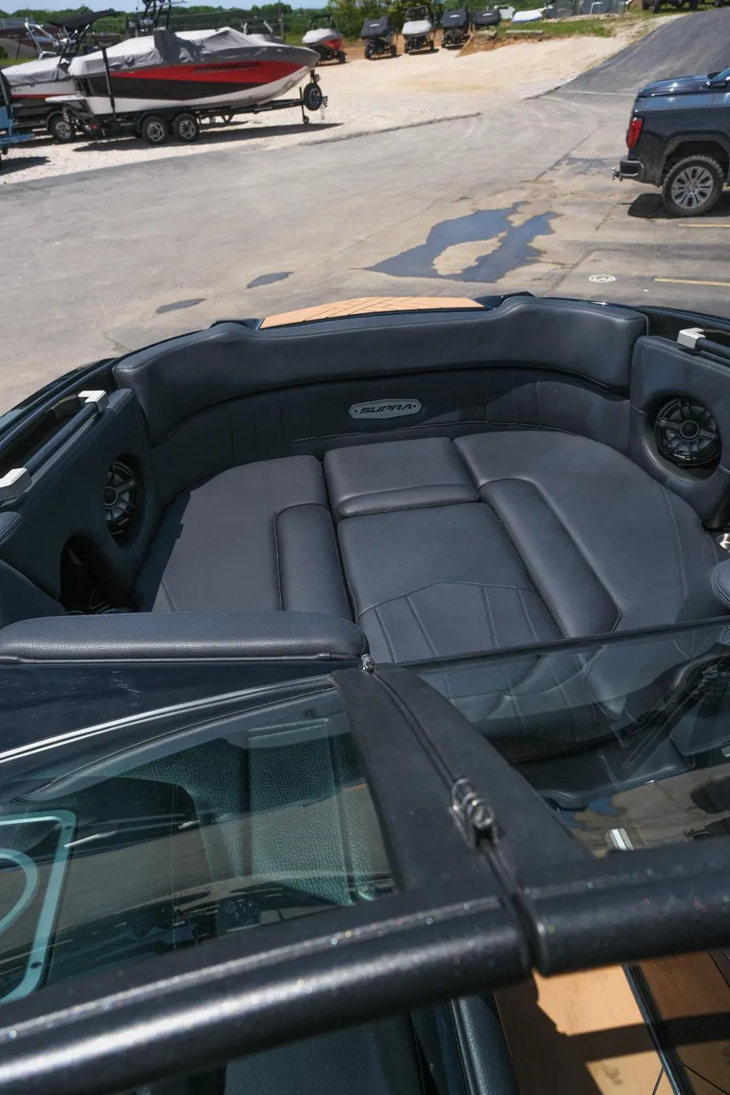 Slide: The Image of 2019 Supra SE450 boat interior with black seating, docked near other boats. - 29