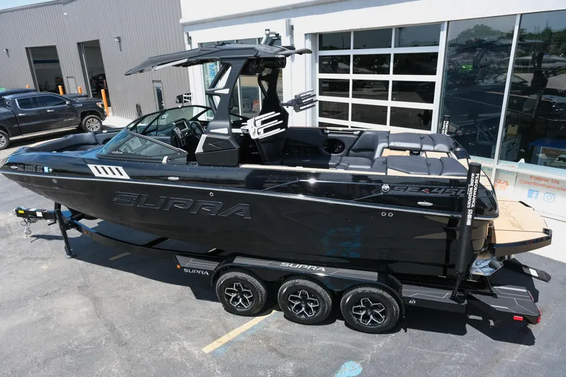 Slide: The Image of 2019 Supra SE450 boat on trailer, sleek black design, parked outside a building. - 3