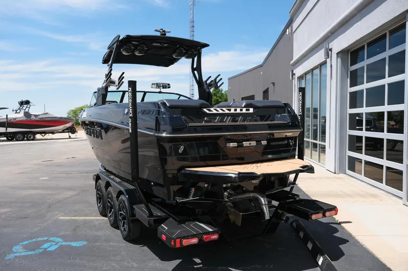 Slide: The Image of 2019 Supra SE450 boat on trailer, parked outside a building under clear blue sky. - 7