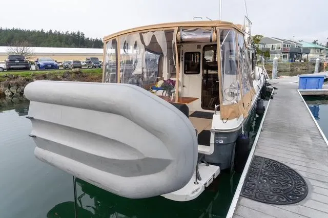 Slide: The Image of 2015 Ranger Tugs R-31 CB docked, featuring a covered deck and inflatable dinghy. - 13