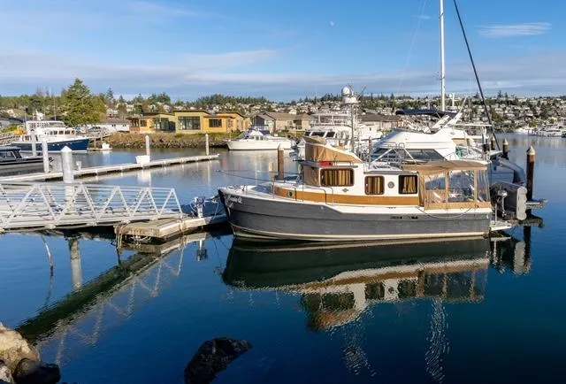 Slide: The Image of 2015 Ranger Tugs R-31 CB docked at a marina, reflecting on calm water. - 3