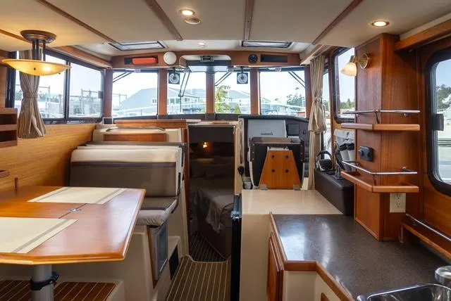 Slide: The Image of Interior of a 2015 Ranger Tugs R-31 CB boat, featuring a cozy dining area and helm. - 4