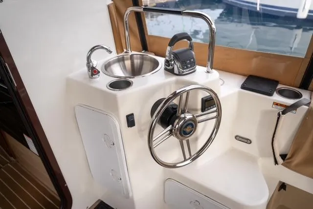 Slide: The Image of 2015 Ranger Tugs R-31 CB helm with steering wheel, sink, and controls. - 9