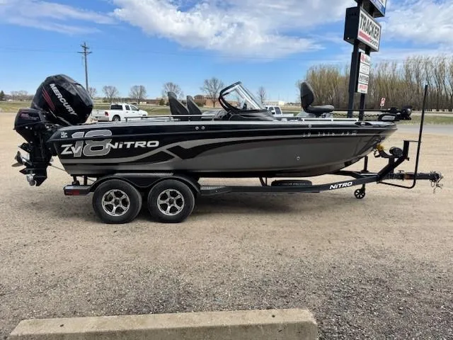Slide: The Image of 2018 Nitro ZV18 fishing boat on trailer, parked outdoors under a partly cloudy sky. - 8