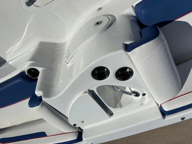 Slide: The Image of 2020 Tahoe 215 Xi boat interior with white and blue seating, cup holders, and storage compartment. - 13