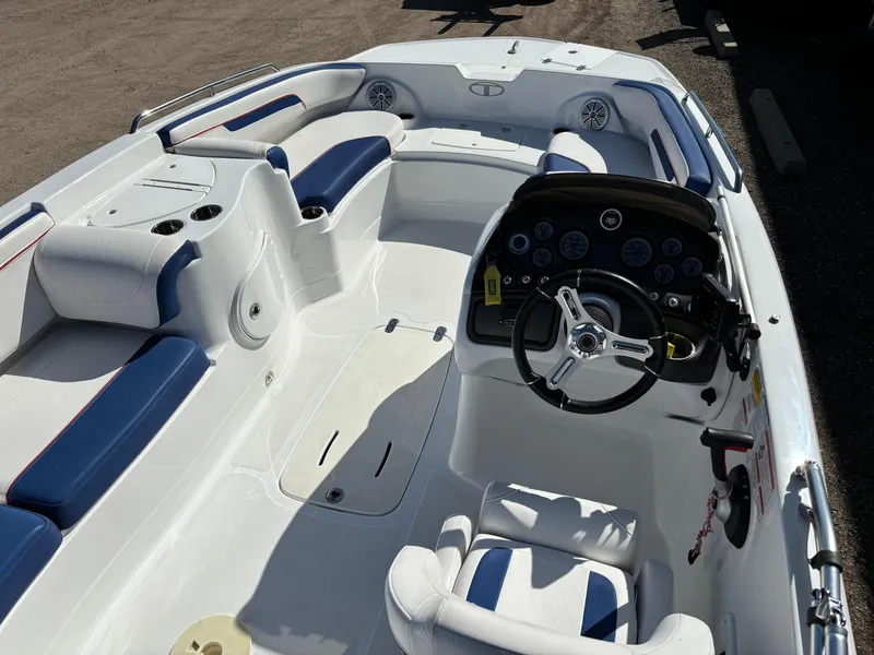 Slide: The Image of 2020 Tahoe 215 Xi boat interior with blue and white seating, steering console, and cup holders. - 7