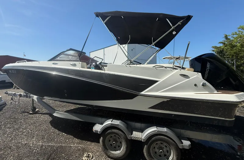 Slide: The Image of 2022 Glastron/Carlson GTD 220 boat on trailer with black canopy, parked outdoors. - 3