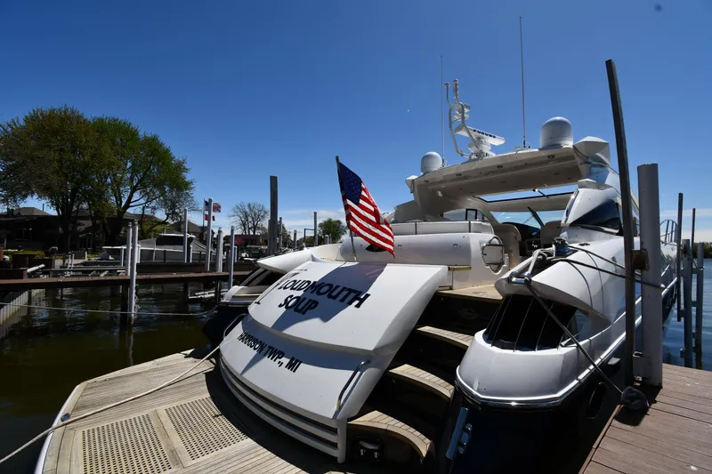 Slide: The Image of Sunseeker 68 Predator 2002 yacht docked, displaying American flag, under clear blue sky. - 3