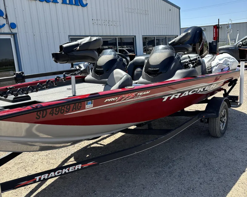 Slide: The Image of 2021 Tracker 175 TXW boat on trailer, parked outdoors under clear blue sky. - 2