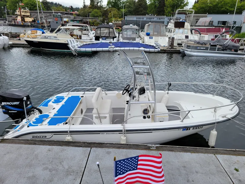 Slide: The Image of 2005 Boston Whaler 180 Dauntless boat docked at a marina with American flag. - 6