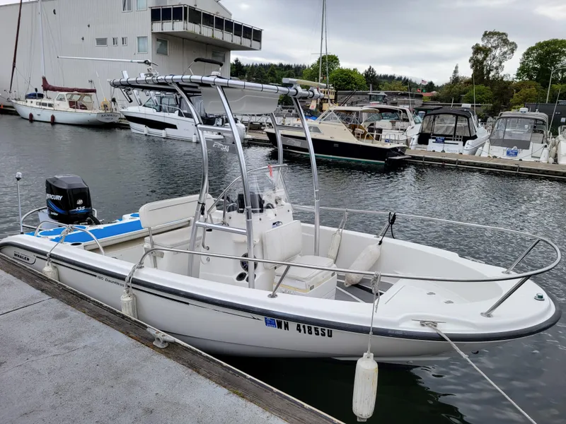 Slide: The Image of 2005 Boston Whaler 180 Dauntless boat docked at a marina, featuring a center console. - 7