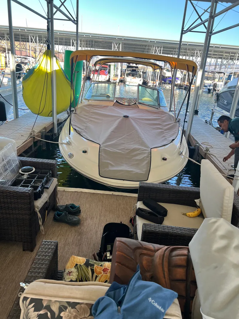 Slide: The Image of 2002 Sea Ray 270 Sundeck docked, covered, with outdoor seating area nearby. - 15