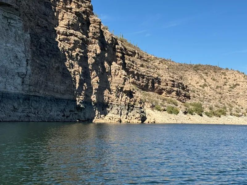 Slide: The Image of Rocky cliffside by a calm lake under a clear blue sky. - 16