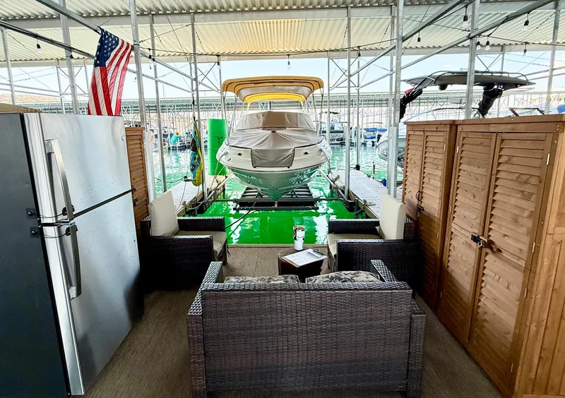 Slide: The Image of 2002 Sea Ray 270 Sundeck docked in a covered marina with seating area and American flag. - 2