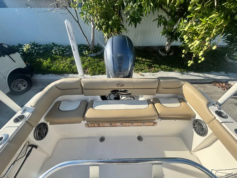 Slide: The Image of 2018 Key West 203 FS boat interior with seating and motor, parked outdoors. - 13