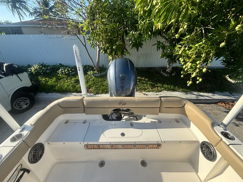 Slide: The Image of 2018 Key West 203 FS boat with outboard motor, parked near greenery and a white fence. - 14