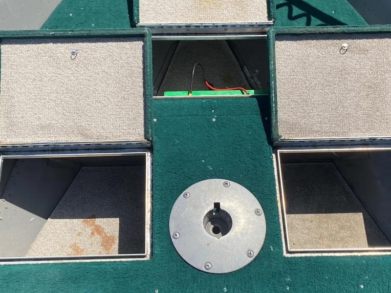 Slide: The Image of 2002 Lund 1650 Explorer boat interior with open storage compartments and green carpet. - 16