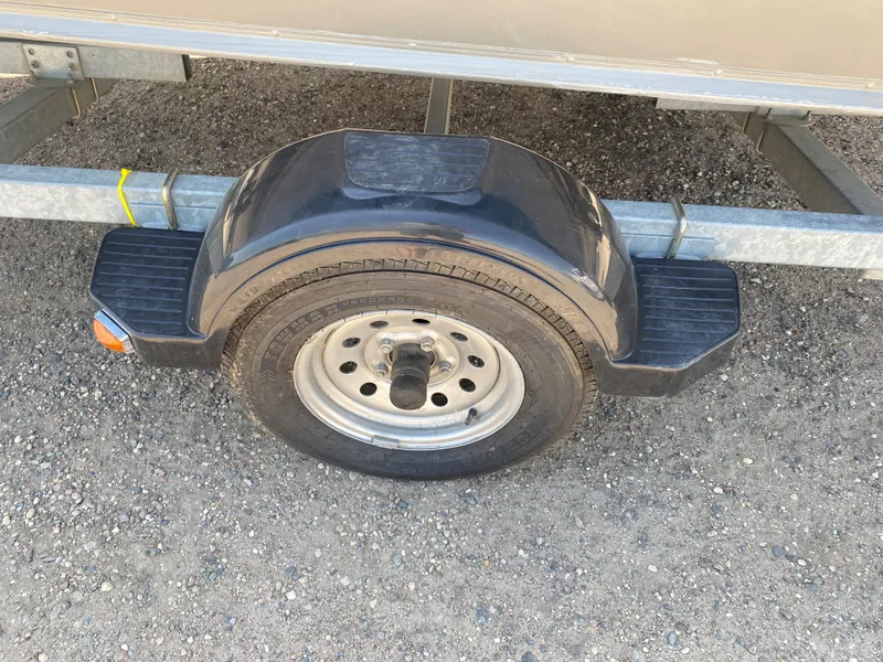Slide: The Image of Trailer wheel and fender of a 2002 Lund 1650 Explorer boat on gravel. - 8