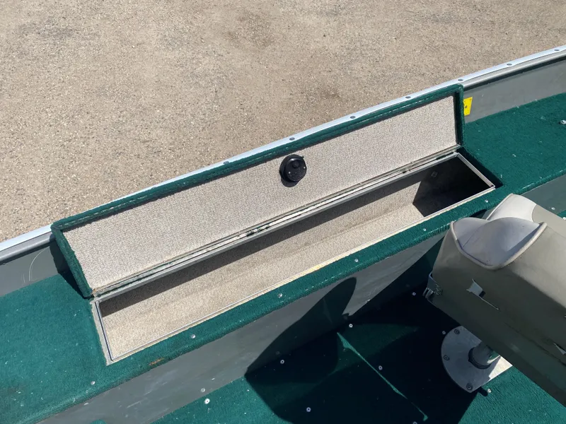 Slide: The Image of 2002 Lund 1650 Explorer boat interior with open storage compartment and green carpet. - 21