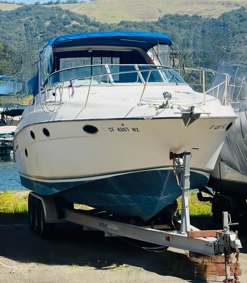 Slide: The Image of 1997 Regal 320 Commodore boat on trailer, blue canopy, parked outdoors. - 0