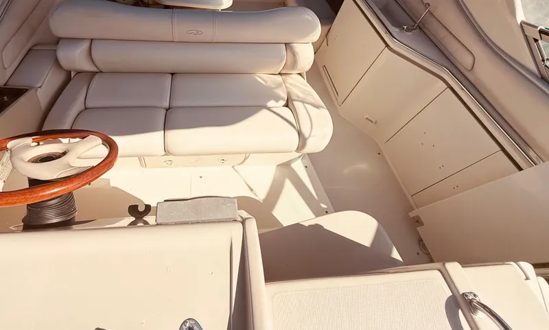 Slide: The Image of Interior of a 1997 Regal 320 Commodore boat with beige seating and wooden steering wheel. - 12