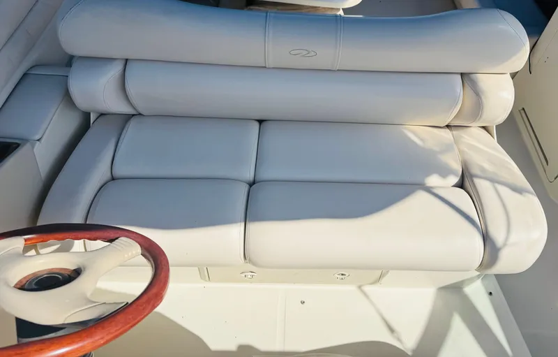 Slide: The Image of White leather seating on a 1997 Regal 320 Commodore boat, featuring a wooden steering wheel. - 13