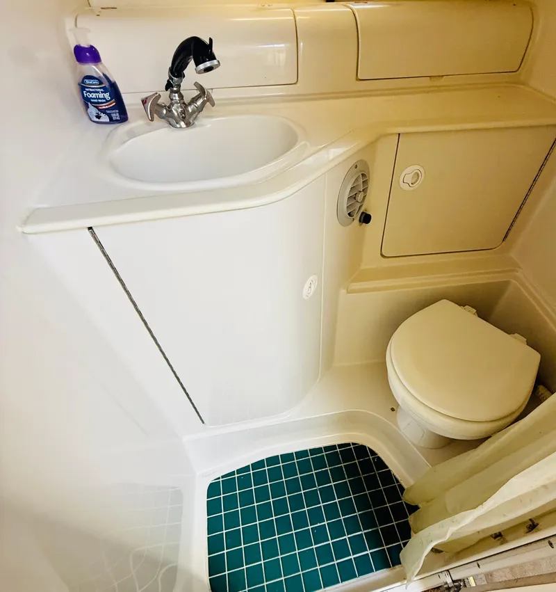 Slide: The Image of Compact bathroom in 1997 Regal 320 Commodore boat with sink, toilet, and green-tiled floor. - 23