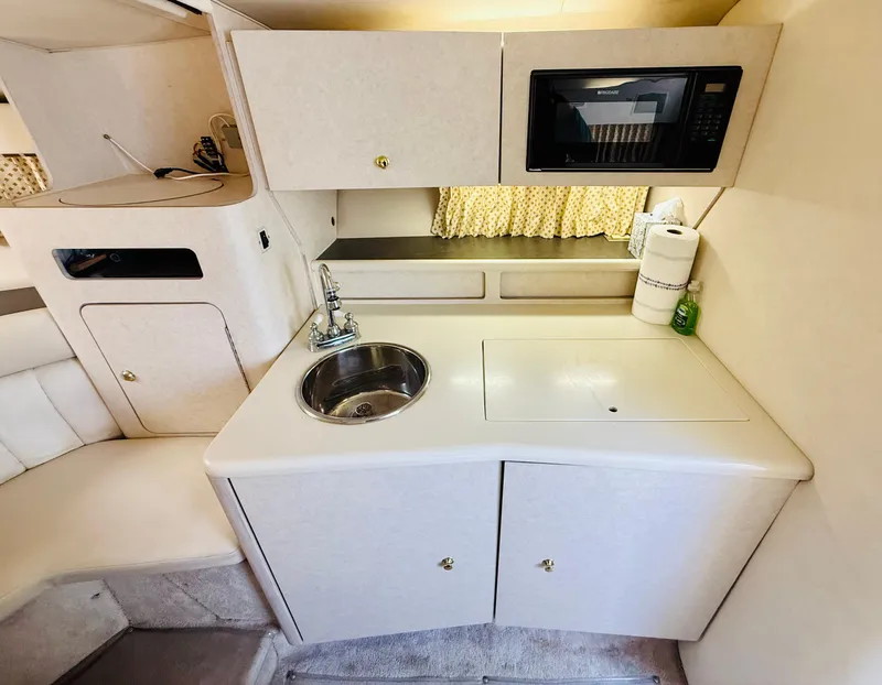 Slide: The Image of Compact kitchen area in a 1997 Regal 320 Commodore boat with sink and microwave. - 26