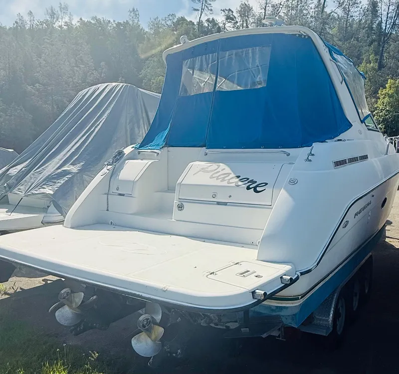 Slide: The Image of 1997 Regal 320 Commodore boat with blue canopy, docked outdoors. - 7