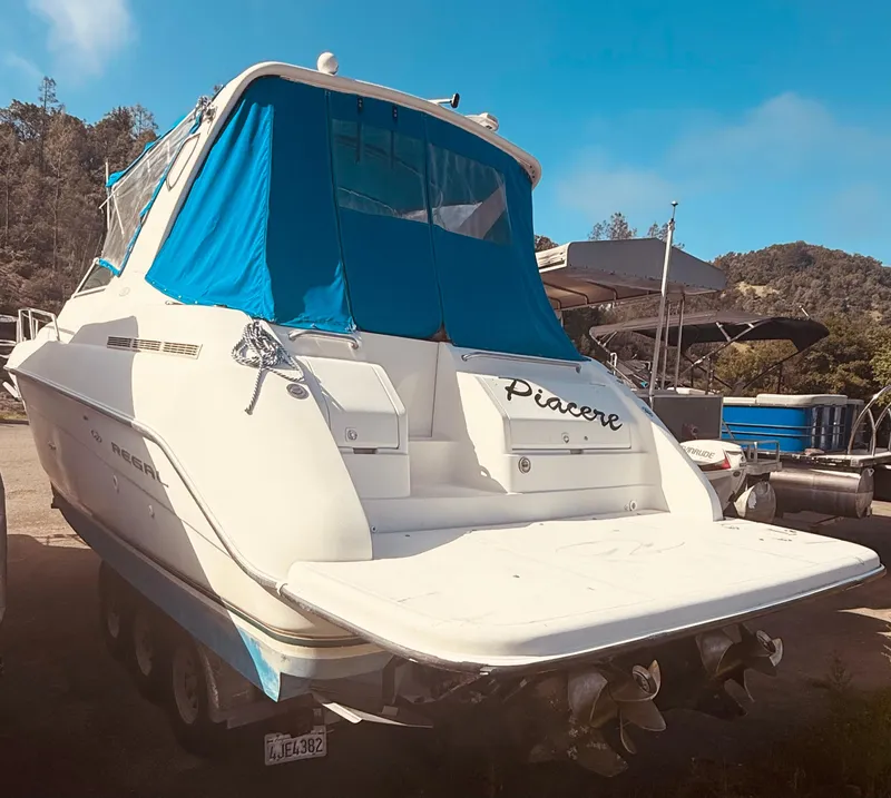 Slide: The Image of 1997 Regal 320 Commodore boat with blue canopy, parked outdoors. - 8