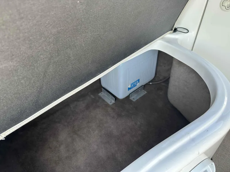 Slide: The Image of Storage compartment in a 2003 Glastron DX 235 boat, featuring a water container. - 15