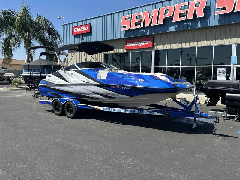Slide: The Image of 2003 Glastron DX 235 boat on trailer outside dealership, vibrant blue and white design. - 17