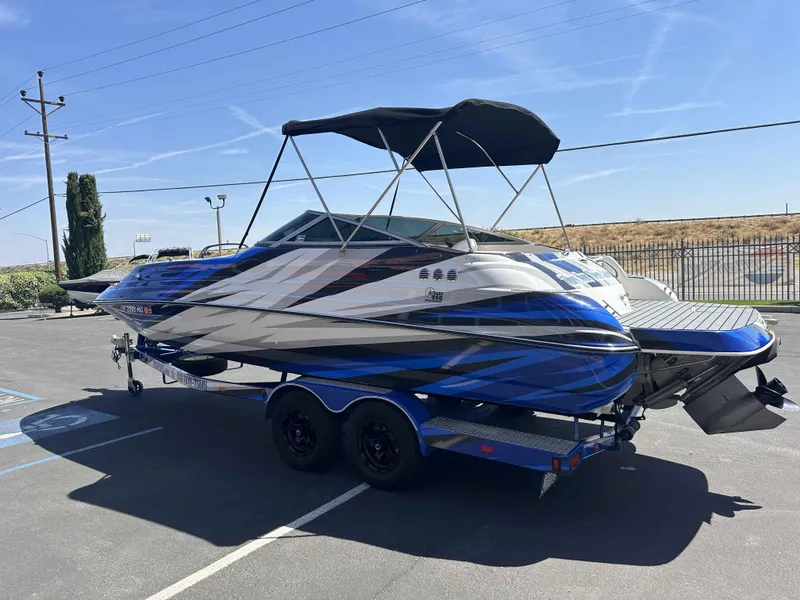 Slide: The Image of 2003 Glastron DX 235 boat with custom blue and white design on a trailer. - 18