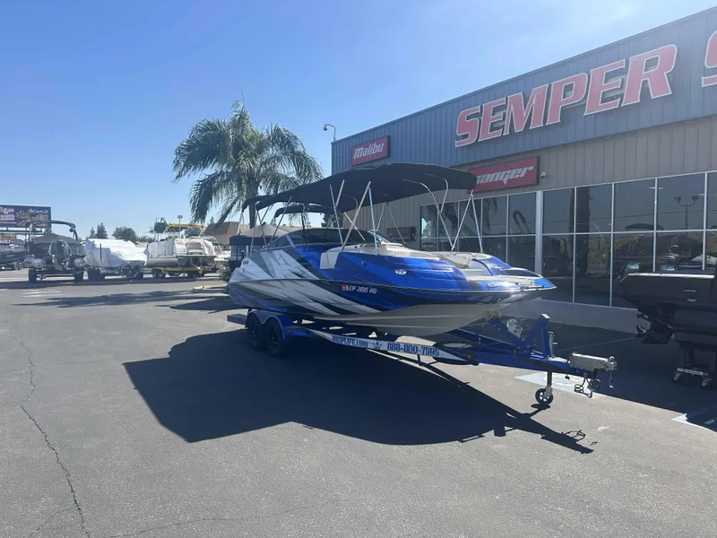 Slide: The Image of 2003 Glastron DX 235 boat on trailer outside dealership under clear blue sky. - 3