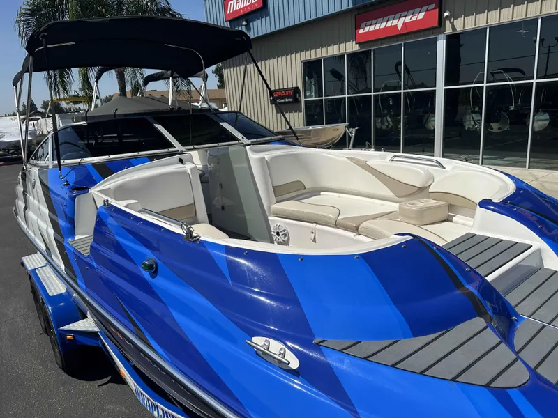 Slide: The Image of 2003 Glastron DX 235 boat with blue exterior and spacious seating, displayed outdoors. - 6