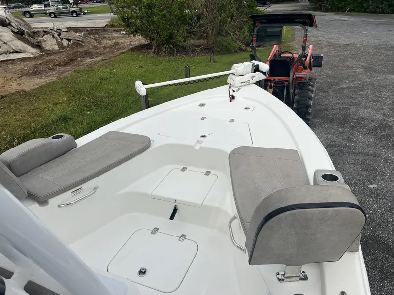 Slide: The Image of 2021 Sea Pro 228 Bay boat with cushioned seating and storage compartments, parked near a tractor. - 4