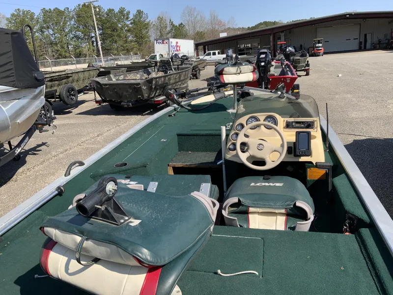 Slide: The Image of 1999 Lowe 180 boat with green interior, steering wheel, and control panel in a parking lot. - 10