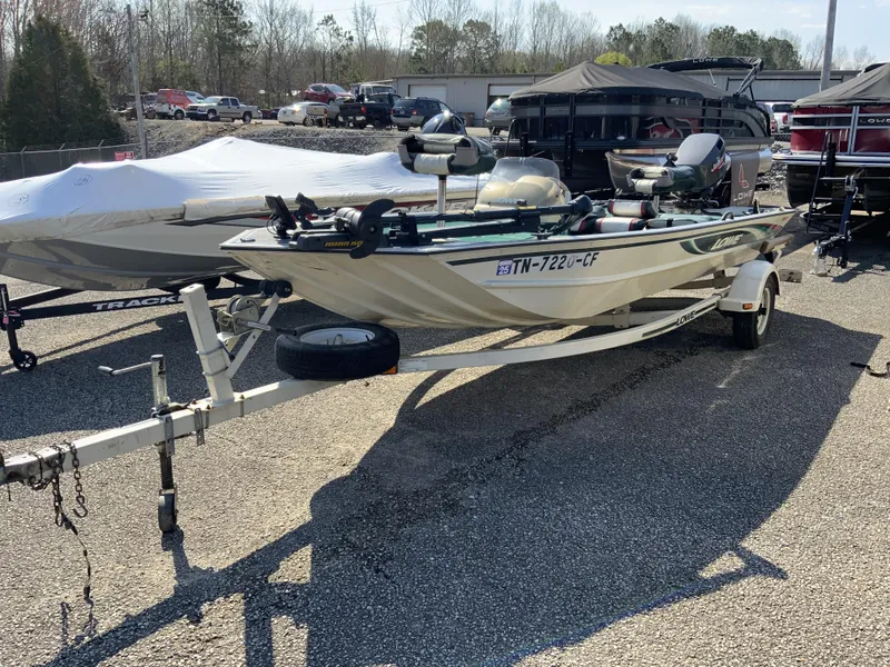 Slide: The Image of 1999 Lowe 180 boat on trailer in parking lot, surrounded by other boats. - 3