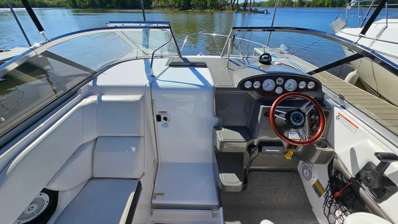 Slide: The Image of 2008 Regal 2565 Window Express boat interior with steering wheel and dashboard, docked by a lake. - 13
