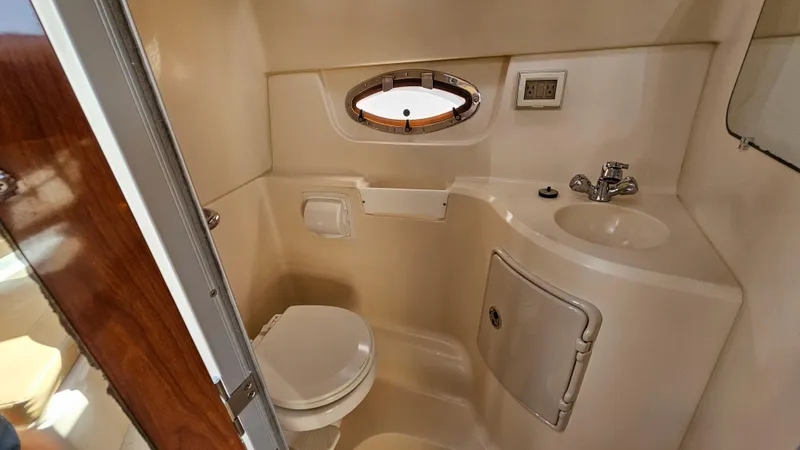 Slide: The Image of 2008 Regal 2565 Window Express boat bathroom with sink, toilet, and porthole window. - 20