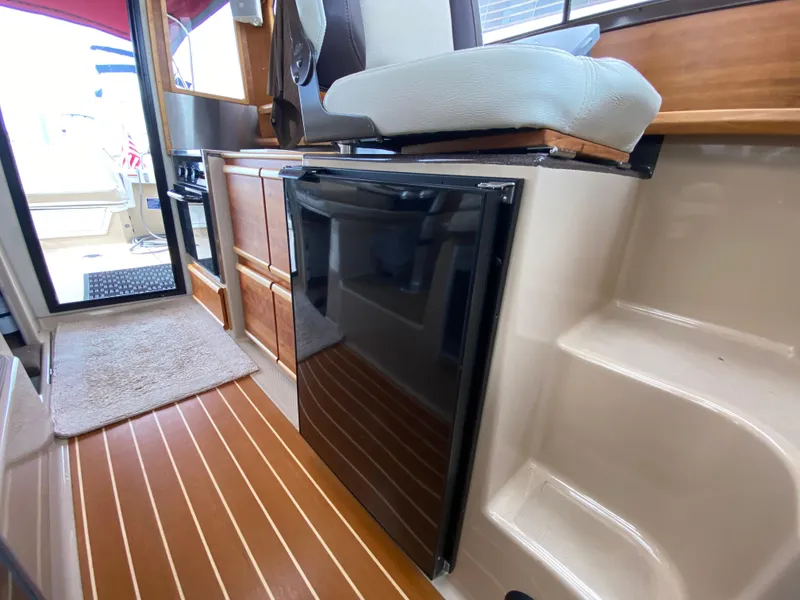 Slide: The Image of 2015 Cutwater C-28 interior with wood flooring, compact kitchen, and seating area. - 31