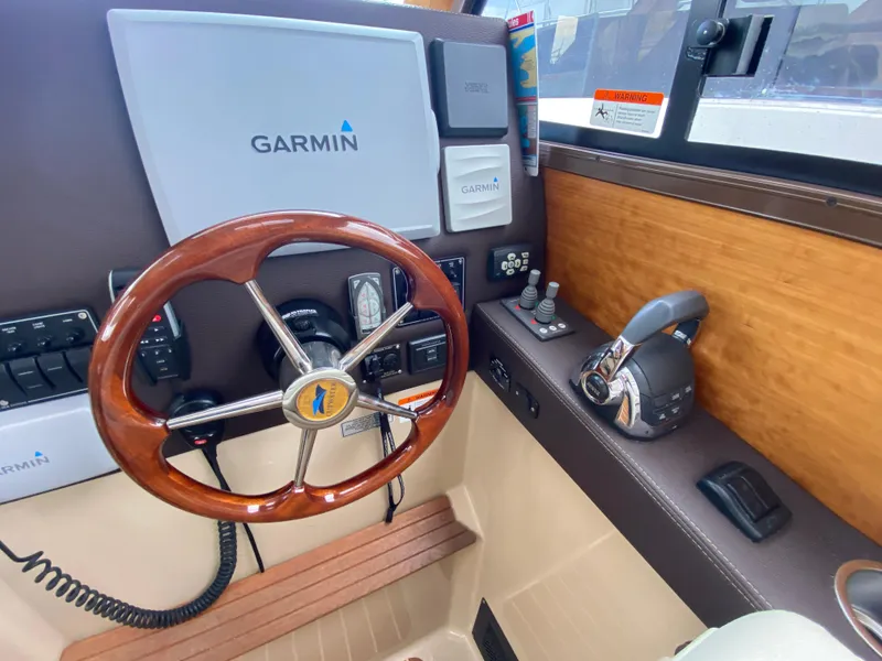 Slide: The Image of 2015 Cutwater C-28 helm with Garmin navigation, wooden steering wheel, and control panel. - 37
