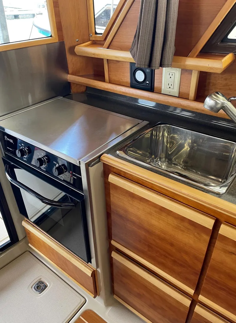 Slide: The Image of 2015 Cutwater C-28 boat kitchen with stove, sink, and wooden cabinetry. - 5